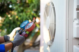 Technician using manifold gauge checking refrigerant for filling home air conditioning and air duct cleaning and maintenance outdoor compressor unit